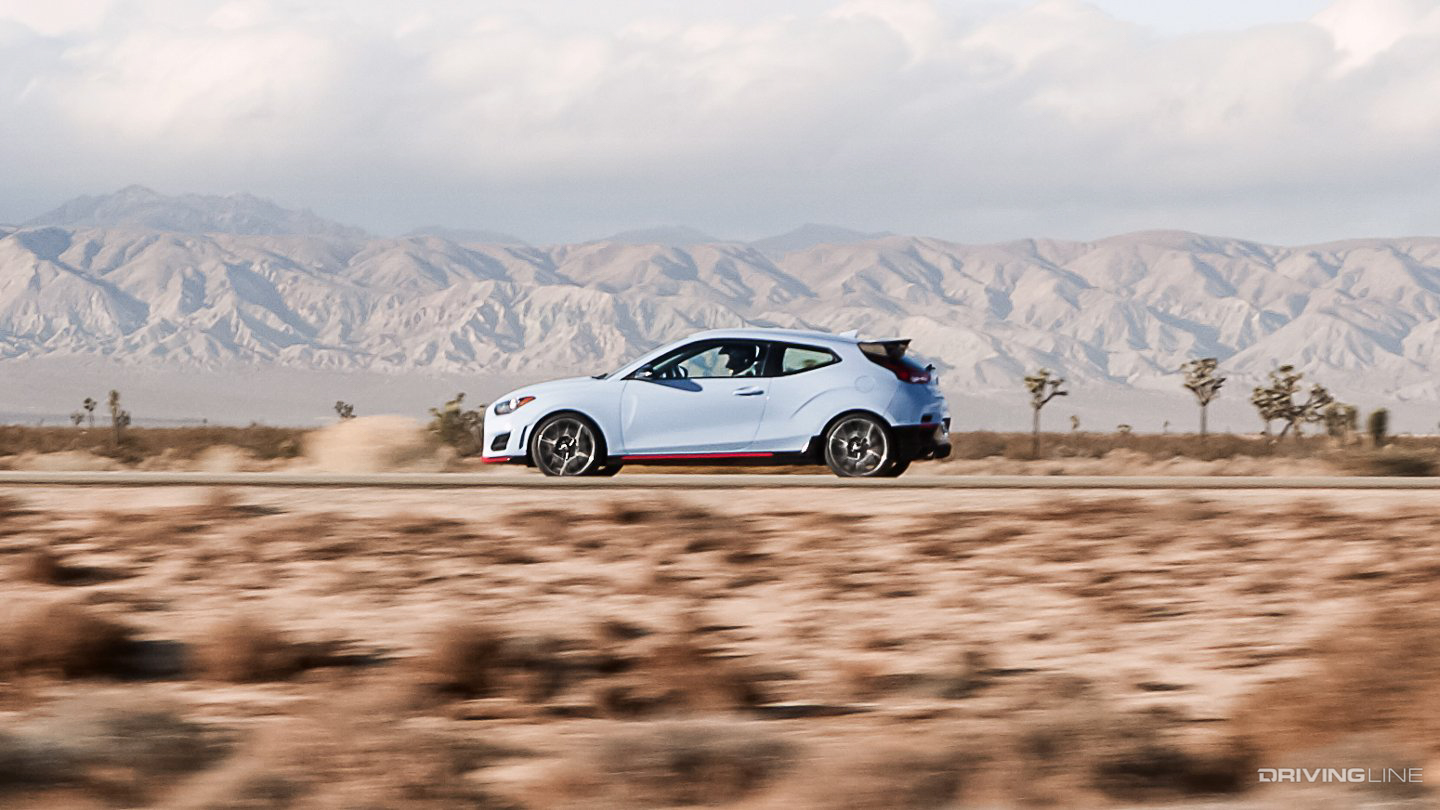Hyundai Veloster N driving along a straight road in the desert
