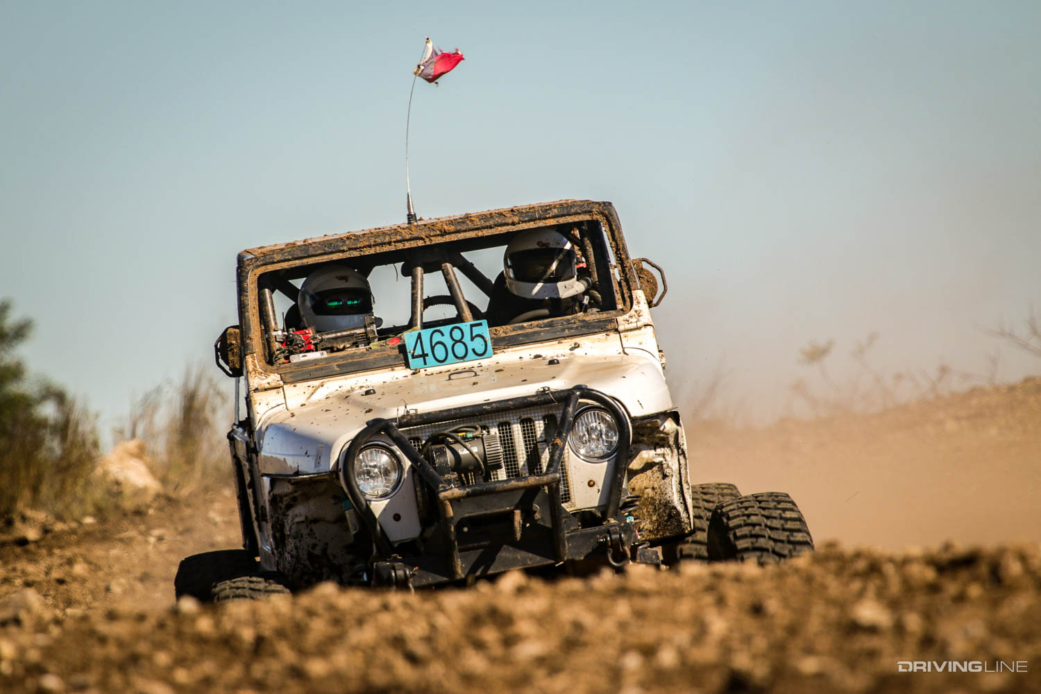 A stock Jeep going over a small hill