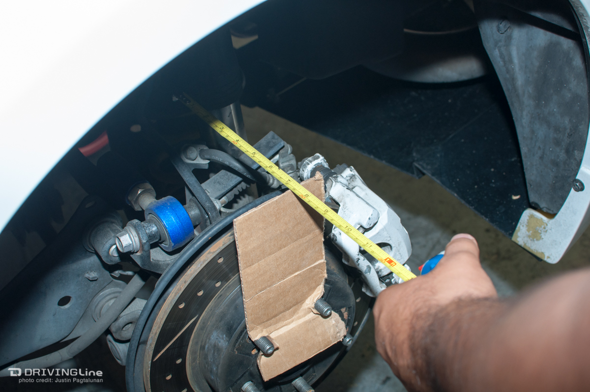 Man measuring distance from hub to back of wheel well