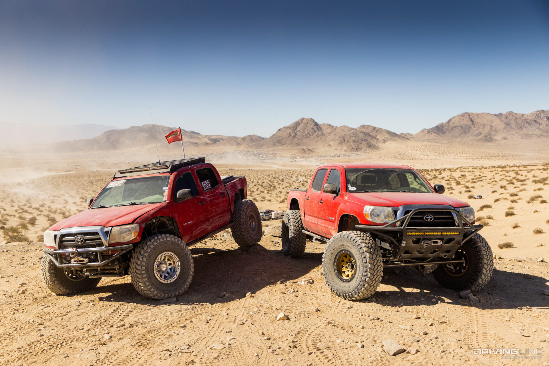 Two red Toyota tacoma trucks on 40-inch Nitto Trail Grappler tires
